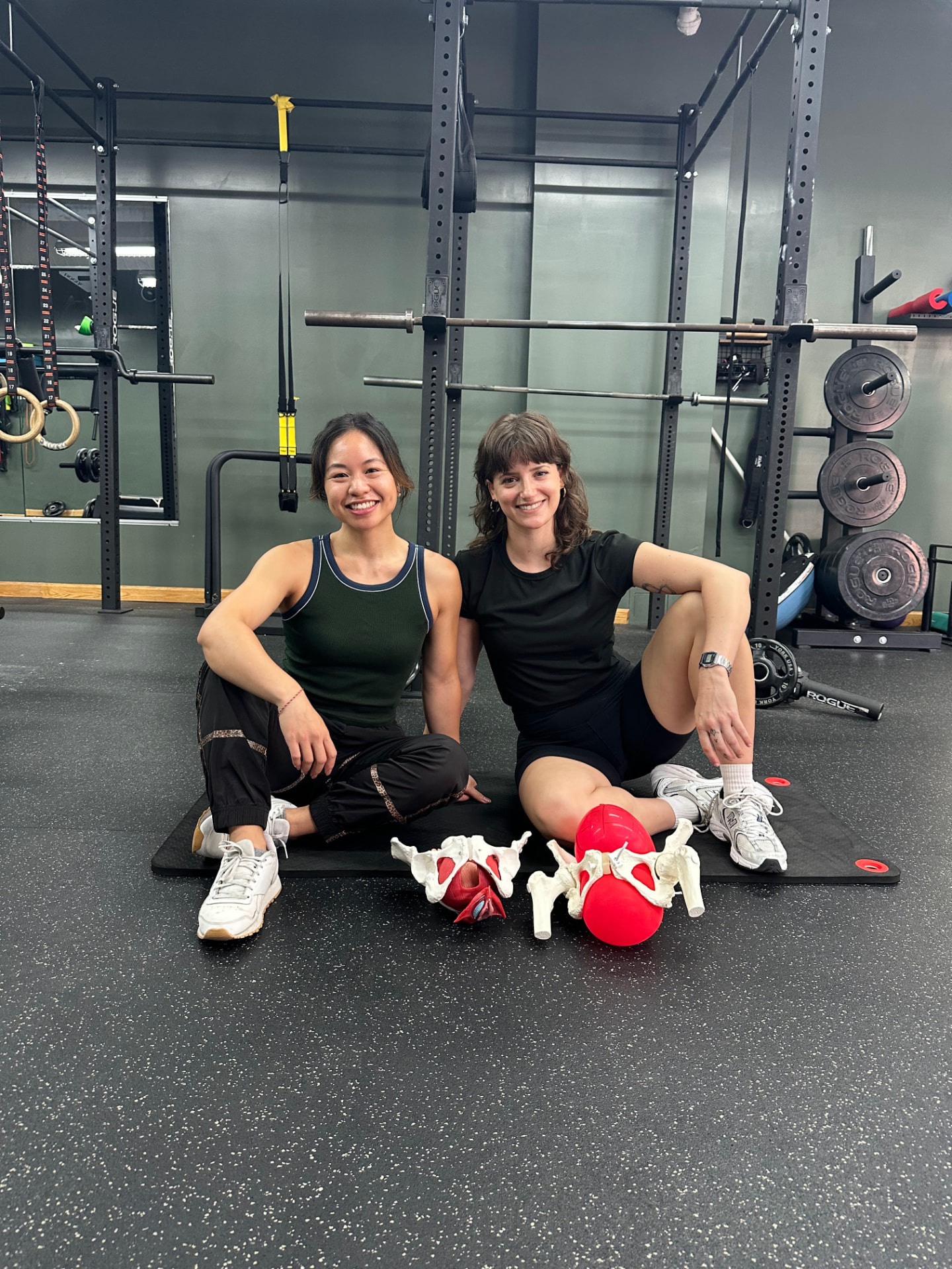 Dr. Iris Platt and Hedda Nguyen sitting in a gym with pelvic anatomy models